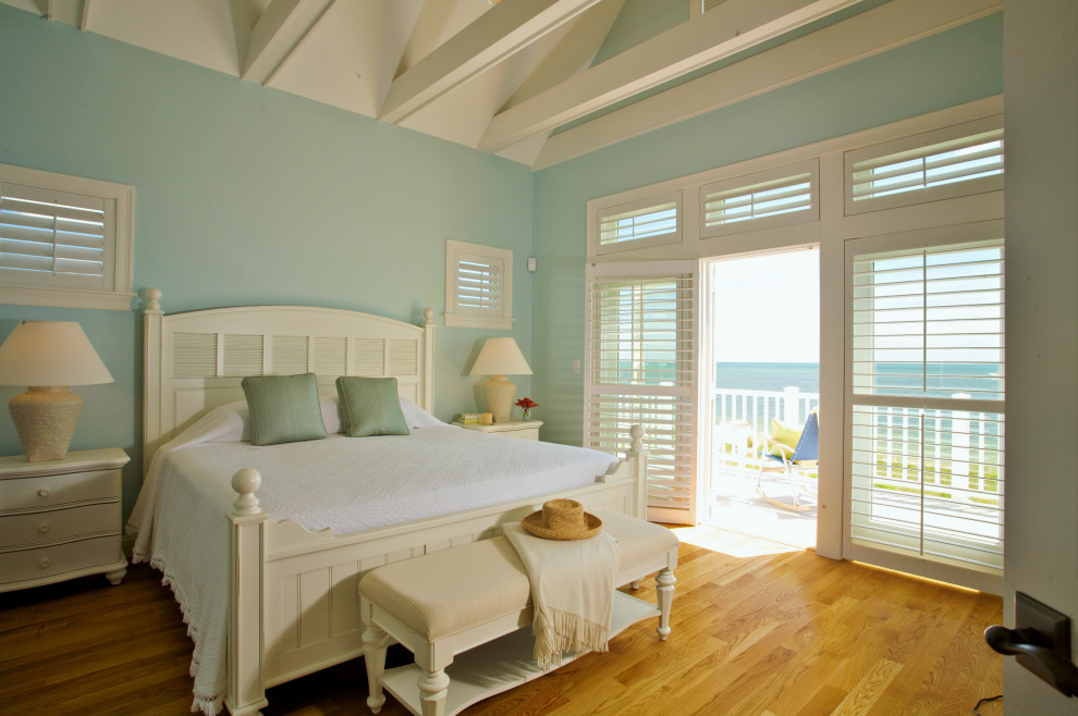 Immagine di una camera da letto costiera con pareti blu, pavimento in legno massello medio, pavimento marrone, travi a vista e soffitto a volta