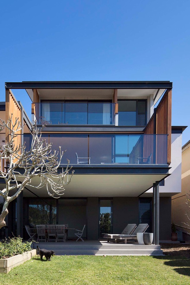 Large contemporary three-storey grey house exterior in Sydney with concrete fiberboard siding, a flat roof and a metal roof.