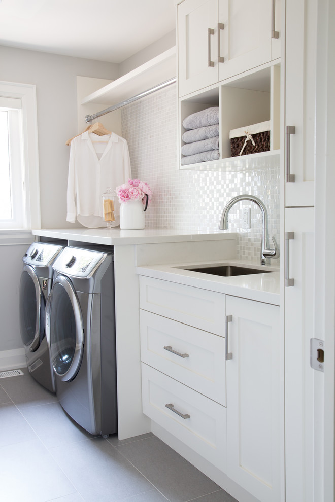 Inspiration for a transitional dedicated laundry room in Toronto with an undermount sink, shaker cabinets, white cabinets, grey walls, a side-by-side washer and dryer, grey floor and white benchtop.