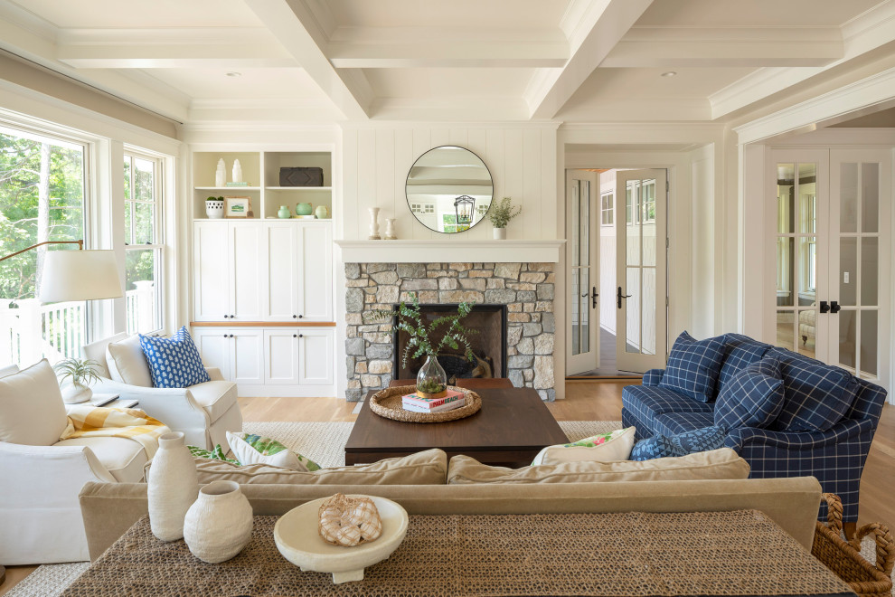 Inspiration for a large coastal open plan living room in Minneapolis with beige walls, light hardwood flooring, a standard fireplace, a stone fireplace surround, a concealed tv and a coffered ceiling.
