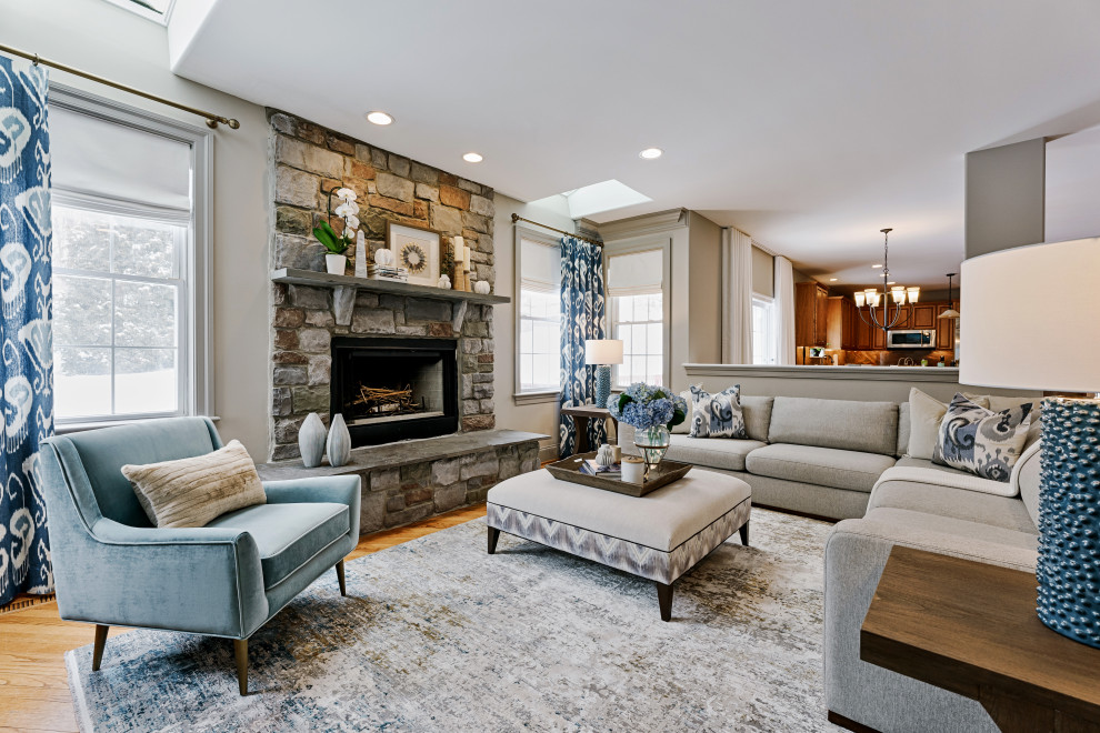 Classic open plan games room in Philadelphia with white walls, medium hardwood flooring, a standard fireplace, a stone fireplace surround, a wall mounted tv and brown floors.