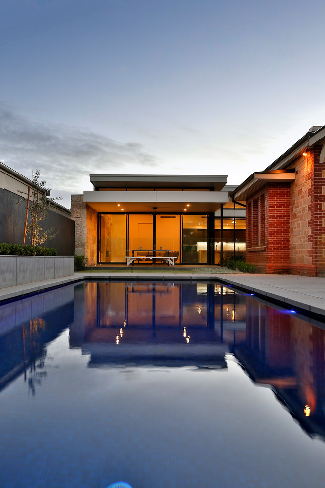 Large contemporary side yard rectangular natural pool in Adelaide with natural stone pavers.