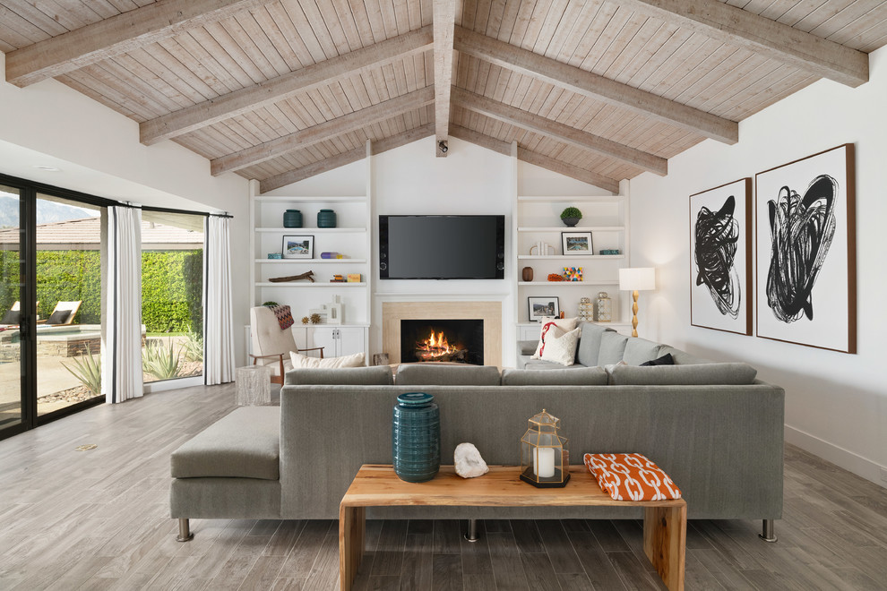 Inspiration for a large beach style family room in Other with white walls, a standard fireplace, a wall-mounted tv and beige floor.