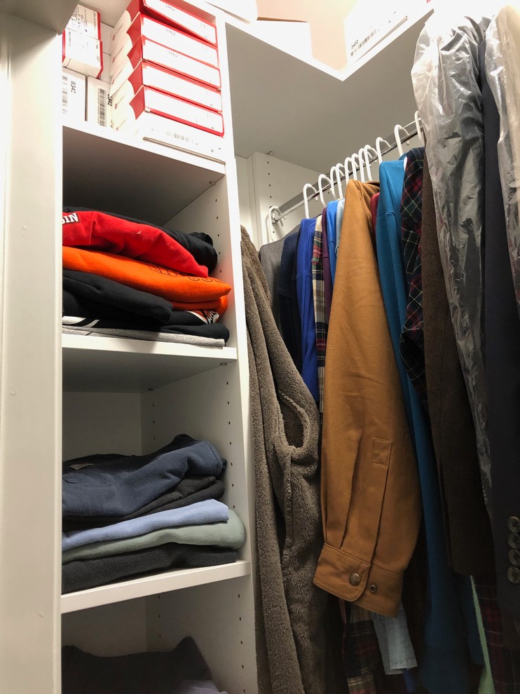 Photo of a small transitional gender-neutral walk-in wardrobe in Chicago with open cabinets, white cabinets, medium hardwood floors and brown floor.