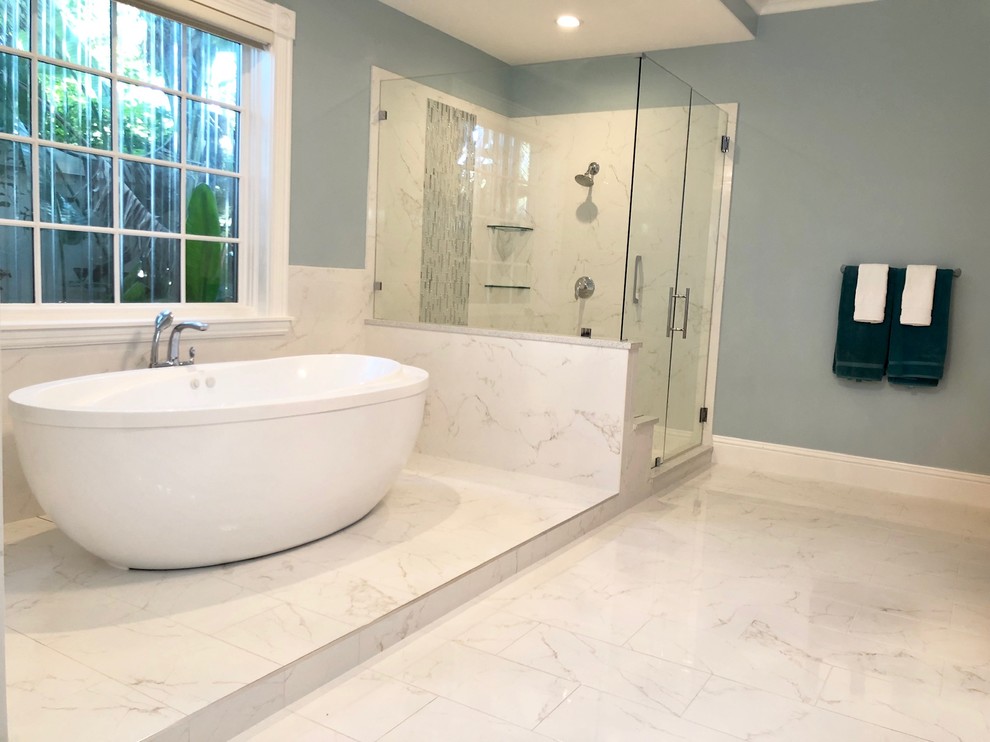 Inspiration for a large modern master bathroom in Tampa with raised-panel cabinets, light wood cabinets, a freestanding tub, a corner shower, a one-piece toilet, multi-coloured tile, blue walls, white floor, a hinged shower door, an undermount sink, grey benchtops and porcelain floors.