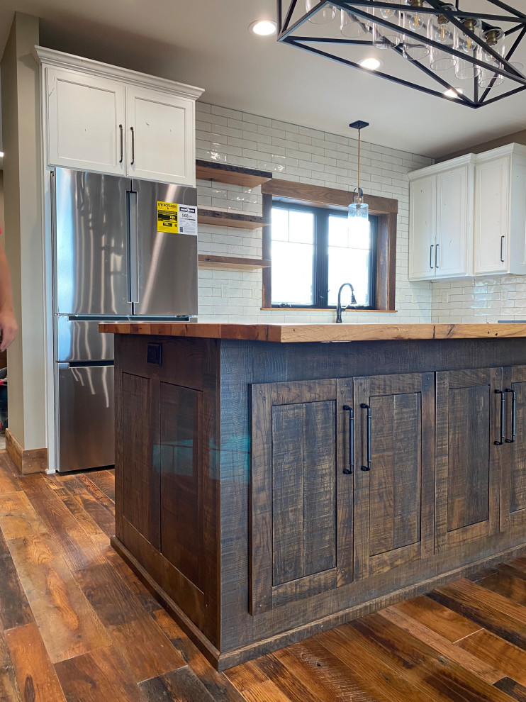 Mid-sized country l-shaped open plan kitchen in Kansas City with a farmhouse sink, shaker cabinets, dark wood cabinets, wood benchtops, white splashback, shiplap splashback, stainless steel appliances, medium hardwood floors, with island, brown floor and brown benchtop.
