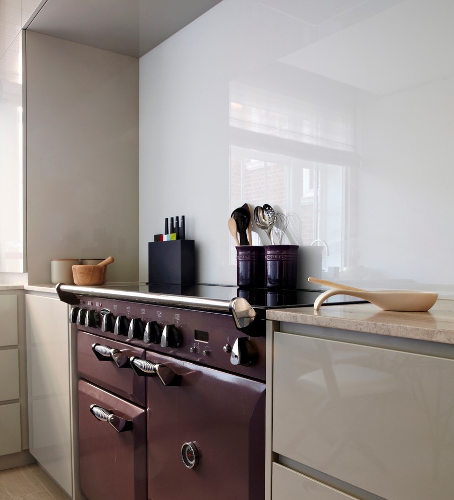 Design ideas for a small contemporary l-shaped separate kitchen in London with a single-bowl sink, flat-panel cabinets, beige cabinets, limestone benchtops, glass sheet splashback, coloured appliances, porcelain floors and no island.