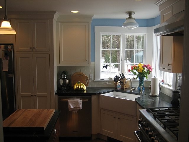 Example of a transitional kitchen design in Boston with a farmhouse sink, white cabinets, white backsplash and stainless steel appliances