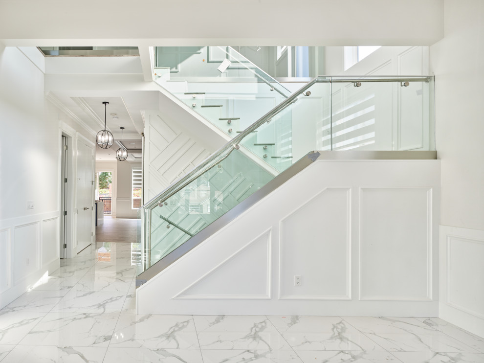 Inspiration for a large modern marble u-shaped staircase in Vancouver with marble risers and glass railing.