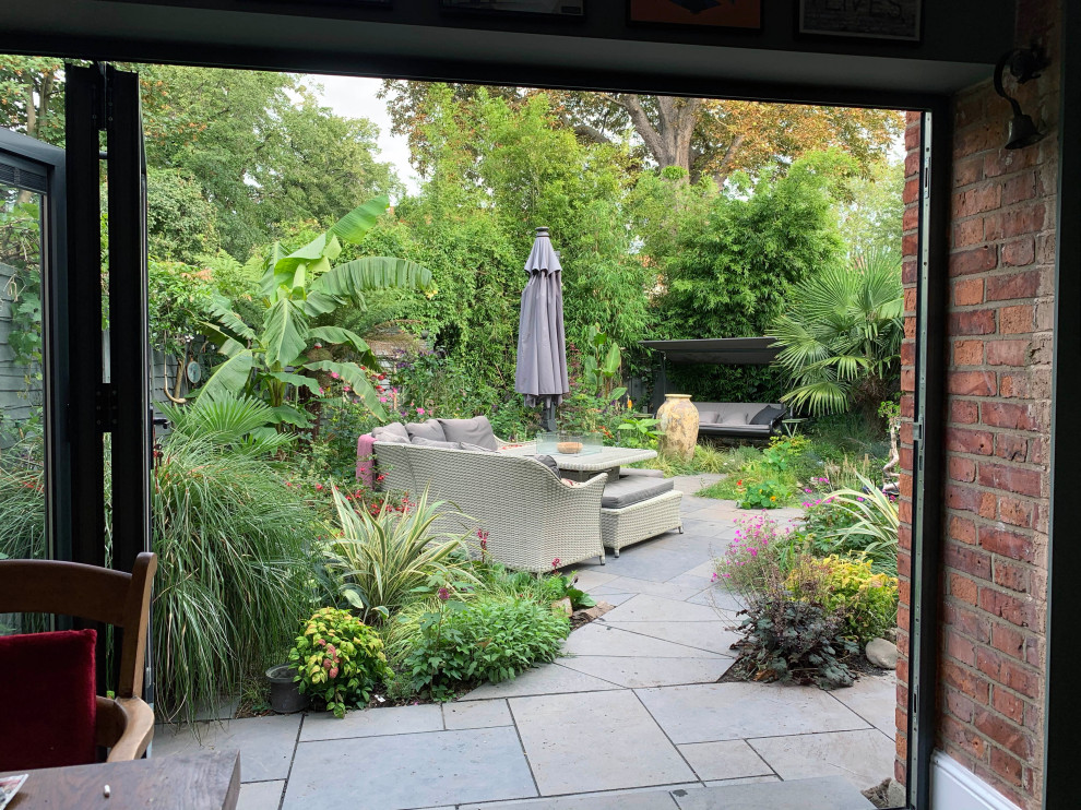 Photo of a medium sized world-inspired back full sun garden for summer in London with natural stone paving, a wood fence and a pond.