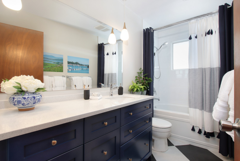 This is an example of a kids bathroom in Edmonton with shaker cabinets, blue cabinets, an alcove tub, white tile, ceramic tile, white walls, vinyl floors, an undermount sink, engineered quartz benchtops, multi-coloured floor, white benchtops, a single vanity and a built-in vanity.
