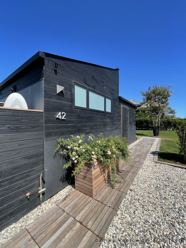 Design ideas for a small and black modern bungalow house exterior in New York with wood cladding, a lean-to roof, a metal roof and a black roof.