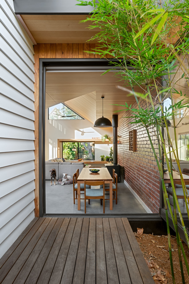 Contemporary open plan dining in Melbourne with white walls, concrete floors, a wood stove and grey floor.