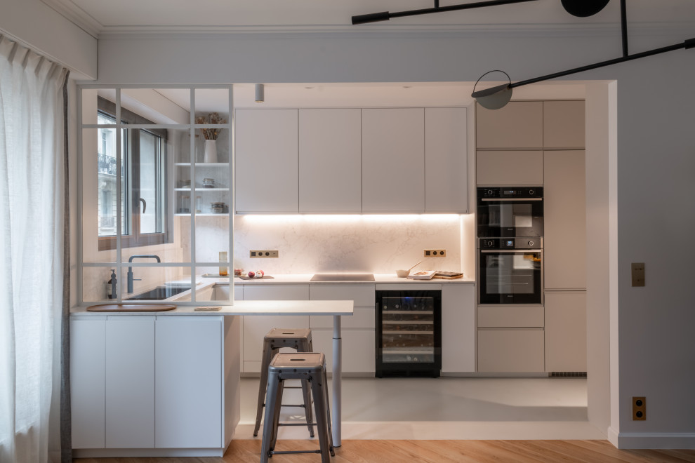 Design ideas for a large contemporary u-shaped open plan kitchen in Paris with a single-bowl sink, beaded inset cabinets, quartzite benchtops, white splashback, engineered quartz splashback, black appliances, concrete floors, beige floor and white benchtop.