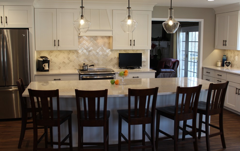 Example of a transitional kitchen design with recessed-panel cabinets, white cabinets, quartz countertops and an island