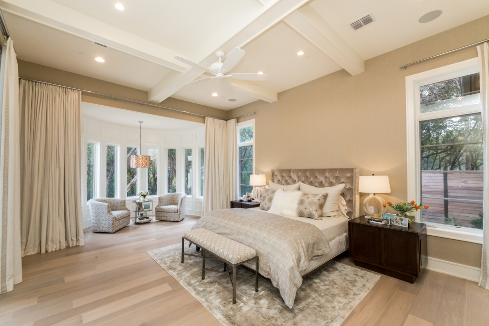 This is an example of a transitional bedroom in Austin with beige walls, light hardwood floors, beige floor and exposed beam.