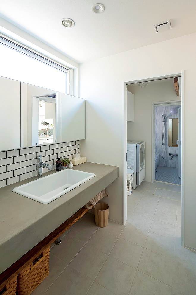 Photo of a contemporary bathroom in Other with open cabinets, white tile, subway tile, white walls, a drop-in sink, concrete benchtops and grey floor.