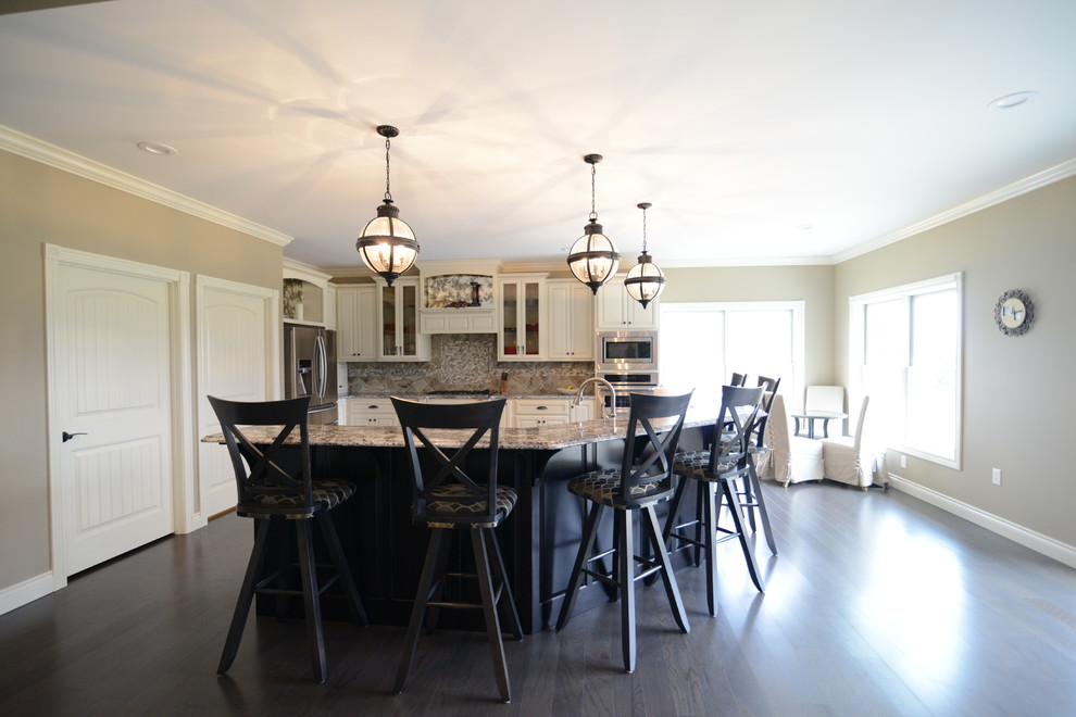 Example of a huge transitional l-shaped medium tone wood floor eat-in kitchen design in Chicago with a farmhouse sink, raised-panel cabinets, white cabinets, granite countertops, gray backsplash, glass tile backsplash, stainless steel appliances and an island