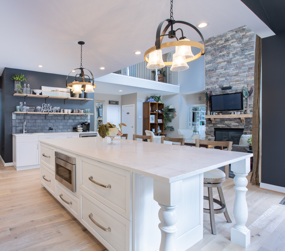 Inspiration for a large traditional u-shaped separate kitchen in DC Metro with recessed-panel cabinets, light wood cabinets, marble benchtops, black splashback, subway tile splashback, panelled appliances, light hardwood floors, with island, beige floor and white benchtop.