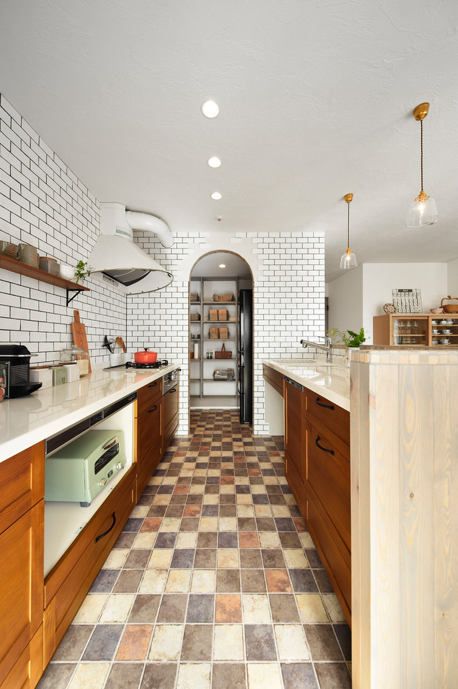 他の地域にある地中海スタイルのおしゃれなキッチン (一体型シンク、落し込みパネル扉のキャビネット、中間色木目調キャビネット、マルチカラーの床) の写真
