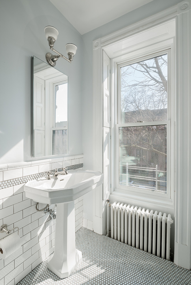 This is an example of a traditional bathroom in New York with a pedestal sink, white walls and mosaic tile floors.