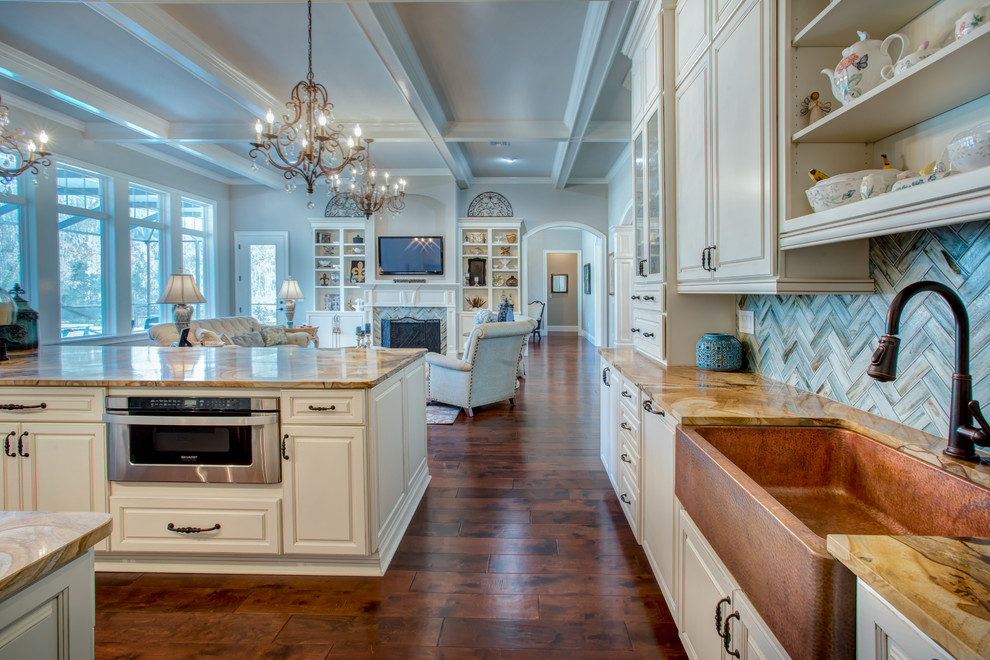 Inspiration for a large transitional l-shaped dark wood floor and brown floor open concept kitchen remodel in Orlando with a farmhouse sink, raised-panel cabinets, white cabinets, granite countertops, blue backsplash, stone tile backsplash, paneled appliances and an island