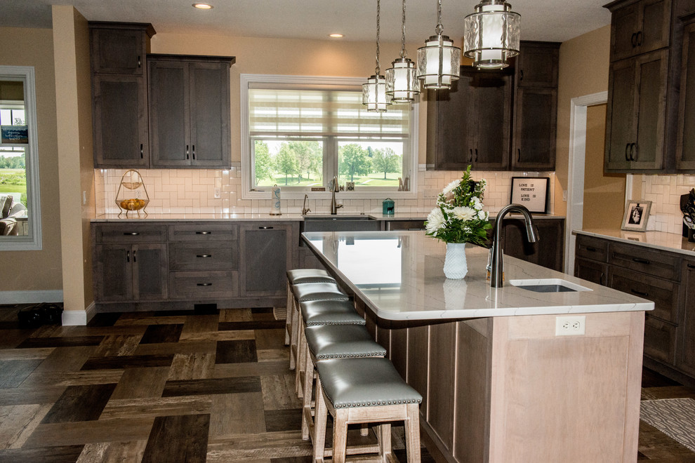 Open concept kitchen - large transitional l-shaped vinyl floor and multicolored floor open concept kitchen idea with a farmhouse sink, shaker cabinets, gray cabinets, quartz countertops, white backsplash, subway tile backsplash, stainless steel appliances, an island and white countertops