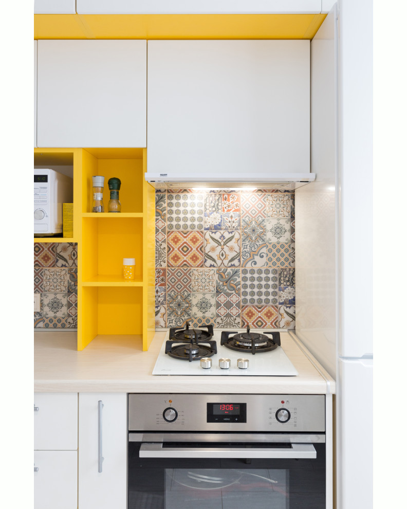 Inspiration for a small contemporary l-shaped separate kitchen in Other with a single-bowl sink, flat-panel cabinets, white cabinets, wood benchtops, multi-coloured splashback, ceramic splashback, stainless steel appliances, laminate floors, beige floor and beige benchtop.