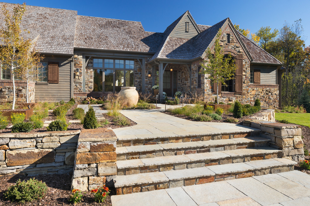 Large country one-storey exterior in Minneapolis with stone veneer and a gable roof.