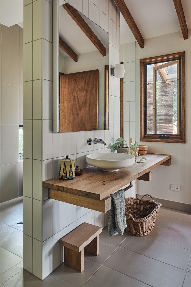 На фото: ванная комната в восточном стиле с фасадами цвета дерева среднего тона, японской ванной, столешницей из дерева и балками на потолке с