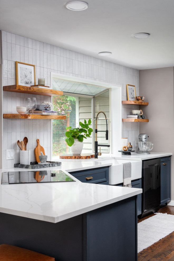 Example of a mid-sized transitional l-shaped dark wood floor and brown floor eat-in kitchen design in Seattle with a farmhouse sink, shaker cabinets, blue cabinets, quartz countertops, white backsplash, porcelain backsplash, stainless steel appliances, a peninsula and white countertops