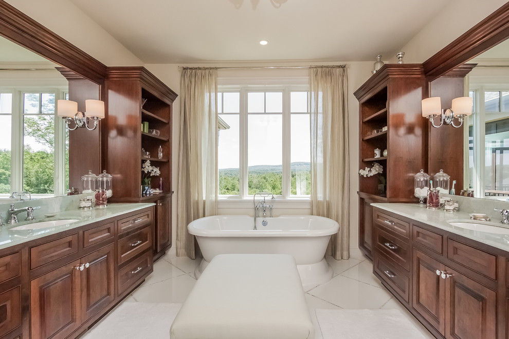 This is an example of a large traditional master bathroom in Boston with an undermount sink, raised-panel cabinets, dark wood cabinets, a freestanding tub, beige walls, porcelain floors and white floor.