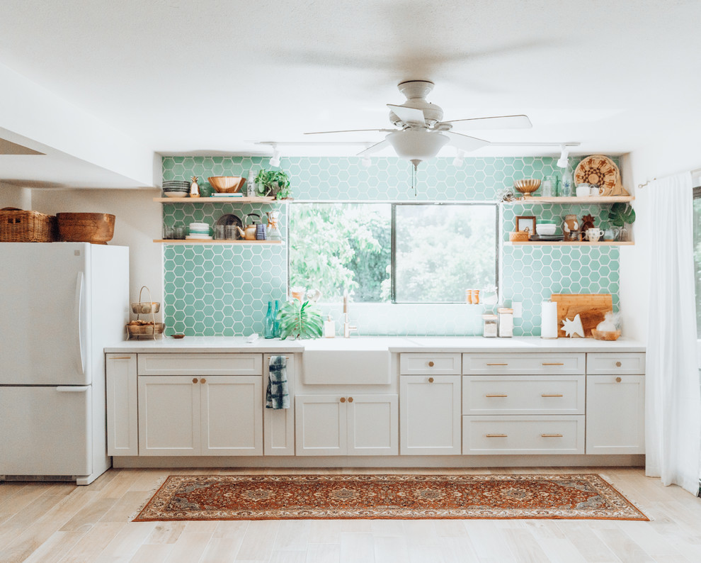 Mid-sized transitional light wood floor kitchen photo in Hawaii with blue backsplash, ceramic backsplash, a farmhouse sink, shaker cabinets, white cabinets, white appliances and no island