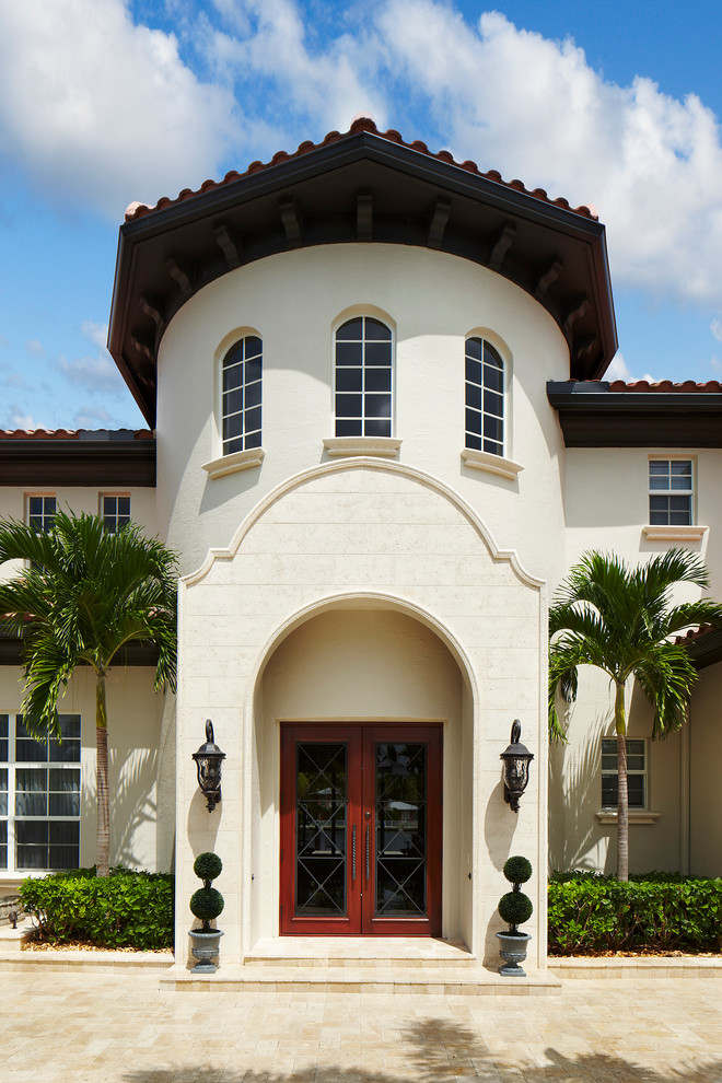This is an example of a large mediterranean two-storey stucco white exterior in Miami with a hip roof.