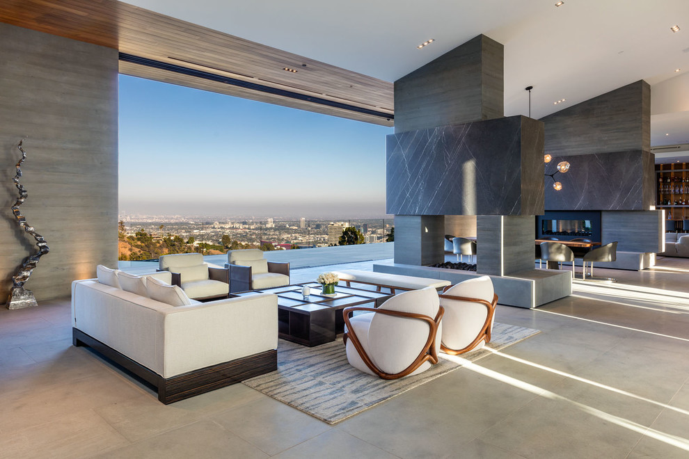 Inspiration for a large contemporary open concept living room in Los Angeles with grey walls, concrete floors, a two-sided fireplace, a concrete fireplace surround, no tv and grey floor.