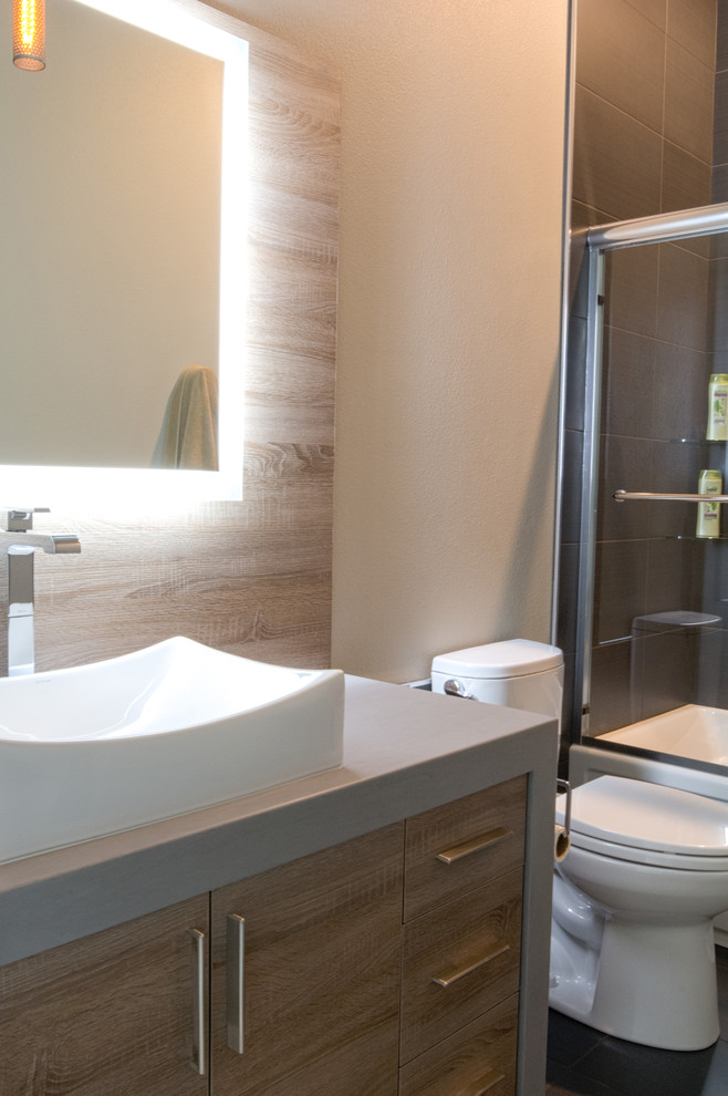 Inspiration for a mid-sized transitional 3/4 bathroom in Other with flat-panel cabinets, medium wood cabinets, a shower/bathtub combo, a one-piece toilet, brown tile, beige walls, a vessel sink, solid surface benchtops, grey floor and a sliding shower screen.