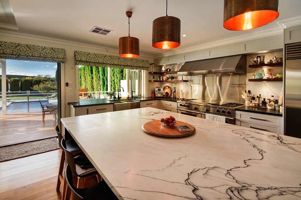Inspiration for a large transitional eat-in kitchen in Other with a double-bowl sink, shaker cabinets, white cabinets, marble benchtops, white splashback, marble splashback, stainless steel appliances, medium hardwood floors, with island and brown floor.