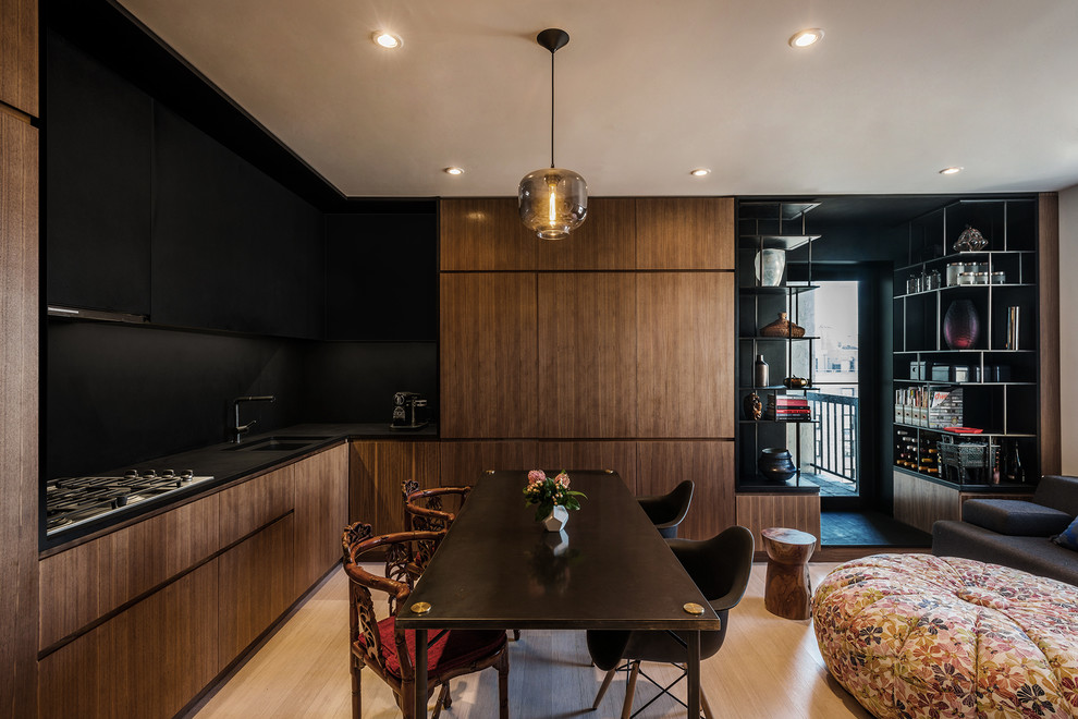 This is an example of a small modern l-shaped eat-in kitchen in New York with bamboo floors, an undermount sink, flat-panel cabinets, medium wood cabinets, solid surface benchtops, black splashback, stone tile splashback and black appliances.