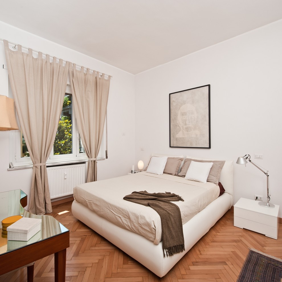This is an example of a contemporary bedroom in Rome with white walls and light hardwood floors.