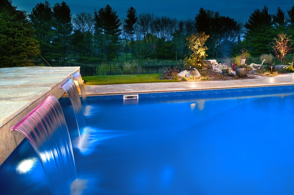 This is an example of a large scandinavian backyard rectangular pool in Minneapolis with a hot tub and natural stone pavers.