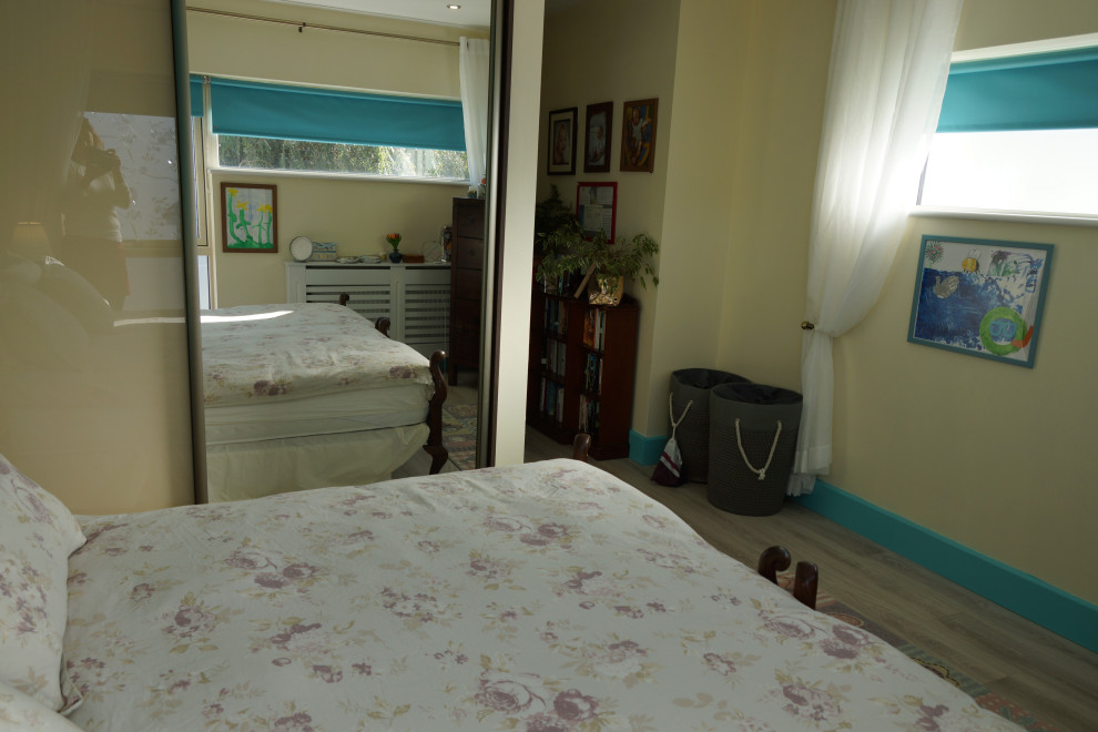 Mid-sized contemporary master bedroom in Dublin with multi-coloured walls, laminate floors and beige floor.