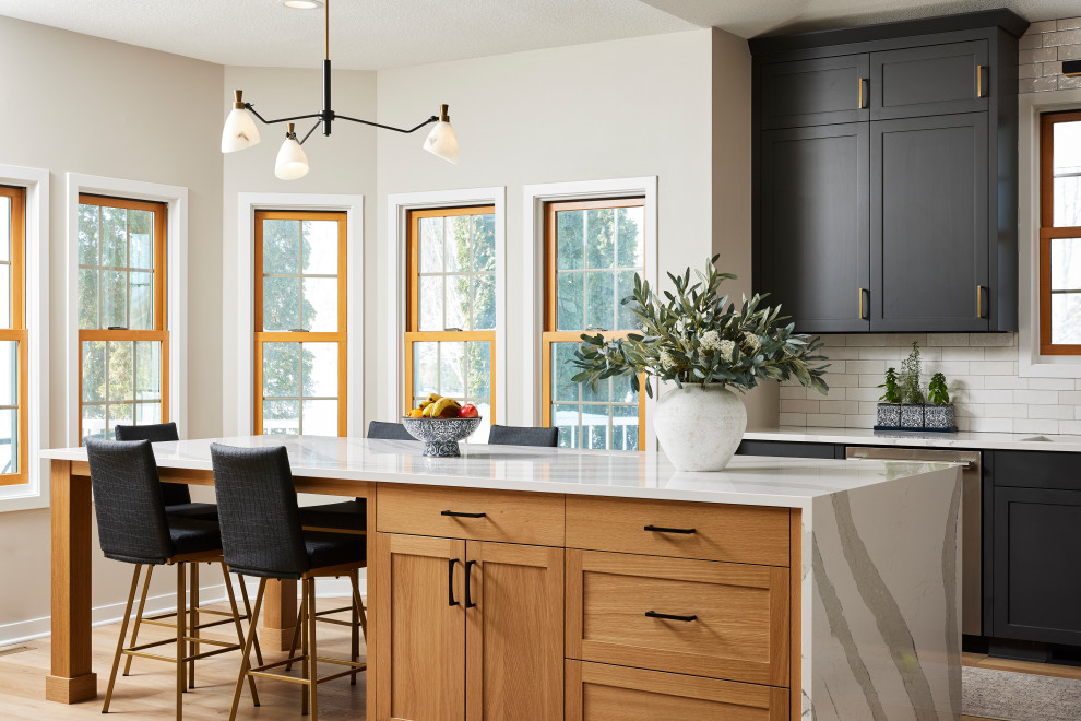 Large transitional l-shaped vinyl floor and brown floor eat-in kitchen photo in Minneapolis with an undermount sink, shaker cabinets, black cabinets, quartz countertops, white backsplash, porcelain backsplash, stainless steel appliances, an island and white countertops