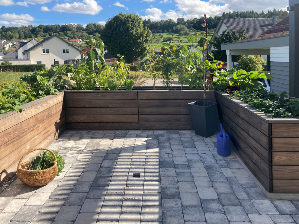 This is an example of a small contemporary side yard partial sun formal garden for summer in Stuttgart with with raised garden bed and concrete pavers.