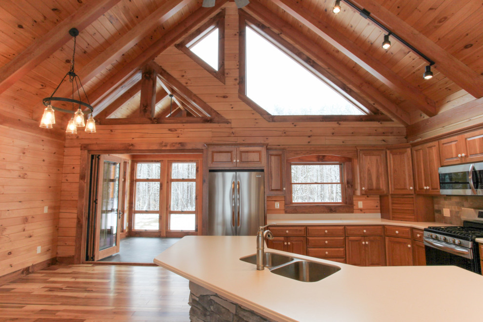 Eat-in kitchen - rustic u-shaped light wood floor, yellow floor and wood ceiling eat-in kitchen idea with a double-bowl sink, raised-panel cabinets, medium tone wood cabinets, wood backsplash, stainless steel appliances, an island and white countertops