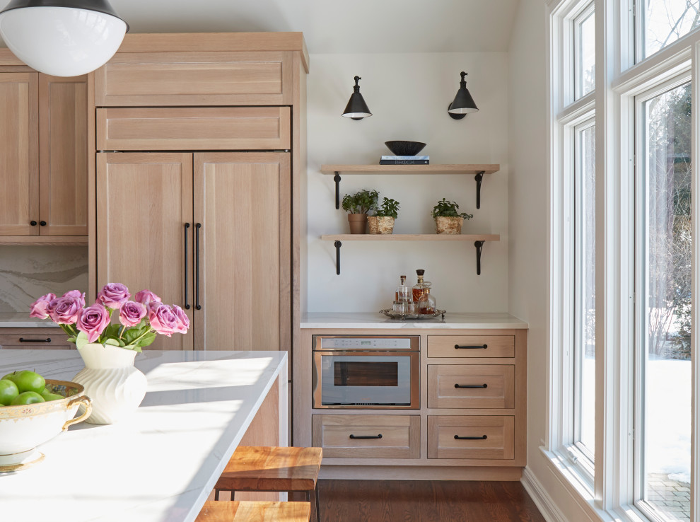 Bild på ett stort vintage vit vitt kök, med en undermonterad diskho, släta luckor, skåp i ljust trä, bänkskiva i kvarts, integrerade vitvaror, mellanmörkt trägolv, en köksö, brunt golv och vitt stänkskydd