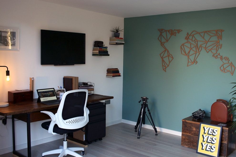 Photo of a medium sized contemporary home studio in Surrey with green walls, light hardwood flooring, a freestanding desk and brown floors.