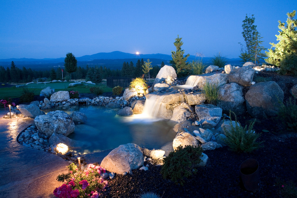 This is an example of a large traditional backyard garden in Seattle with a water feature and natural stone pavers.