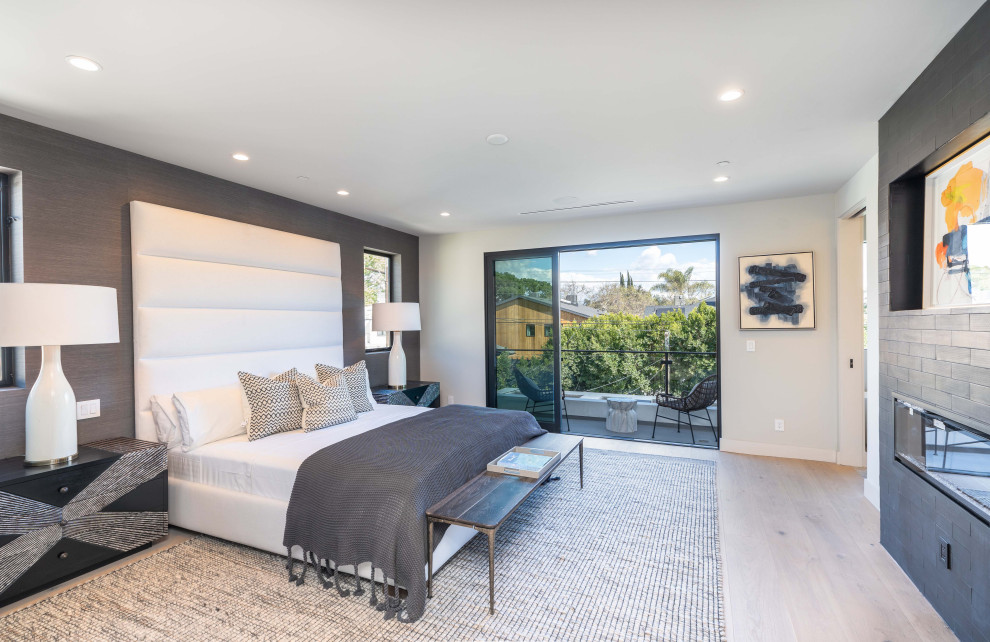 Inspiration for a large modern master bedroom in Los Angeles with white walls, light hardwood flooring, a ribbon fireplace, a tiled fireplace surround, beige floors, wallpapered walls and a feature wall.