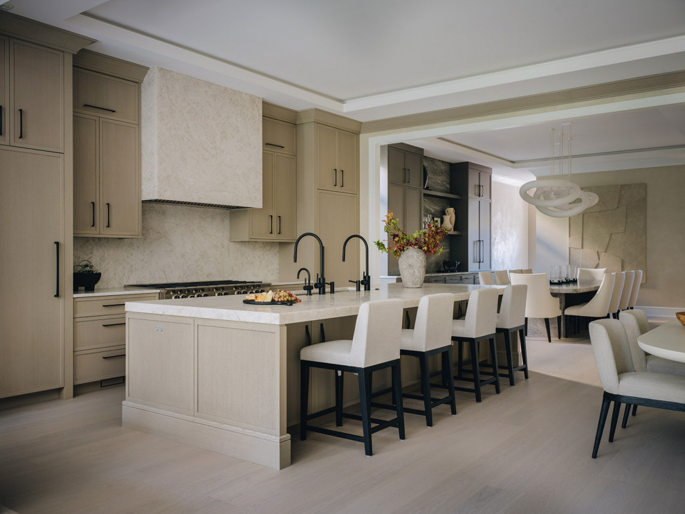 Example of a transitional light wood floor and beige floor kitchen design in Chicago with beige cabinets, quartzite countertops, stone slab backsplash, paneled appliances and an island