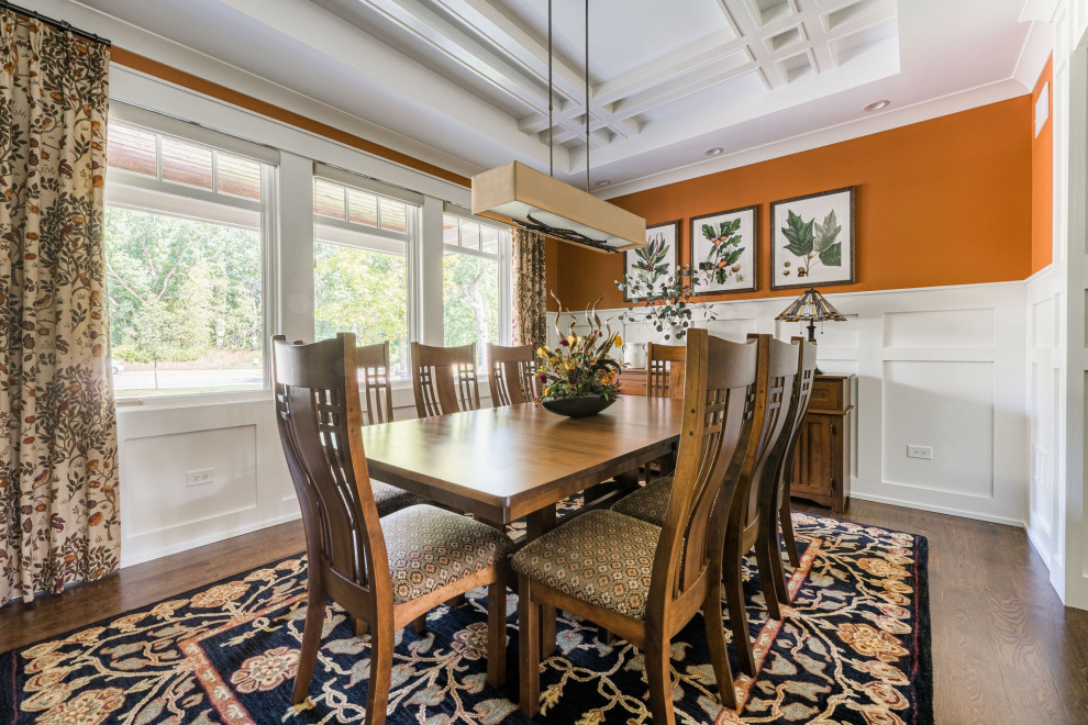На фото: столовая среднего размера в стиле кантри с оранжевыми стенами, паркетным полом среднего тона, коричневым полом, кессонным потолком и панелями на стенах